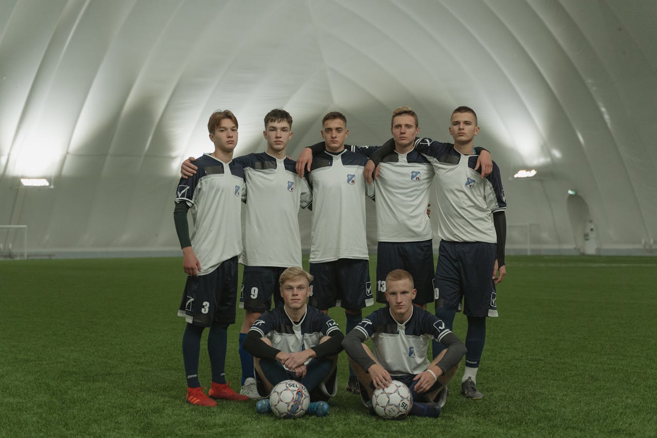 Group of Men in Soccer Uniforms Standing on Green Grass Field